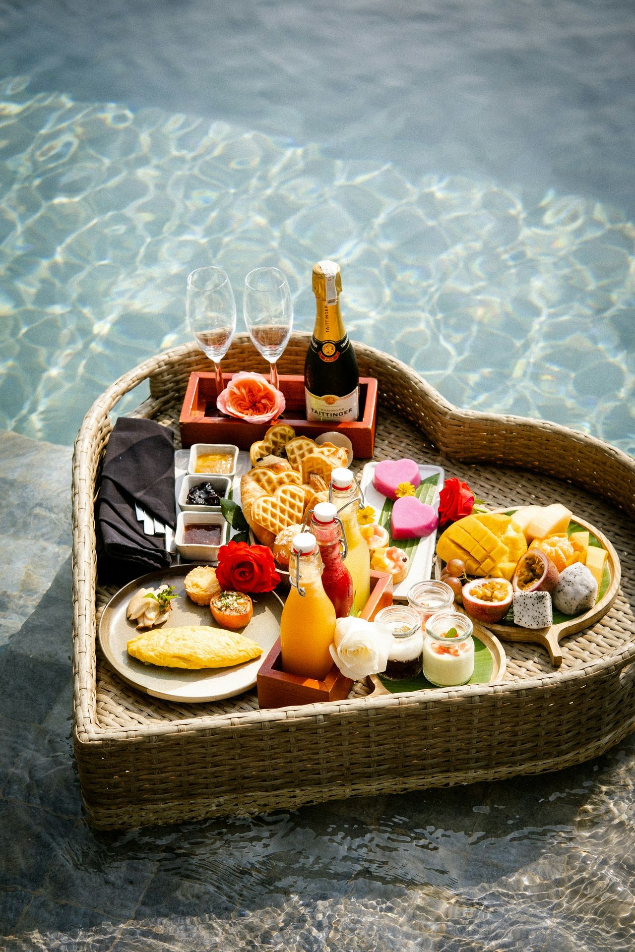 A heart shaped tray filled with food next to a pool